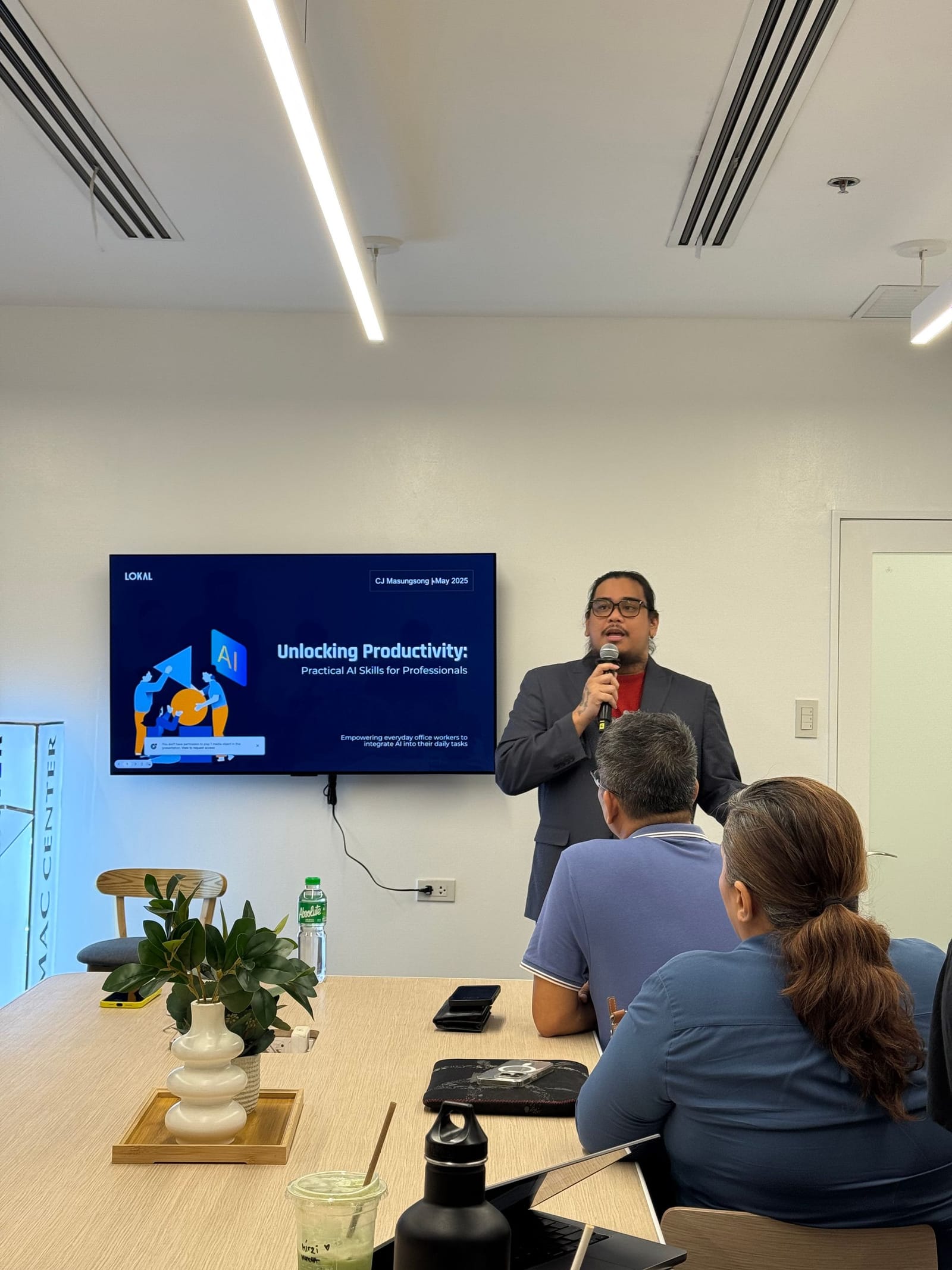 Man speaking at presentation, screen showing 